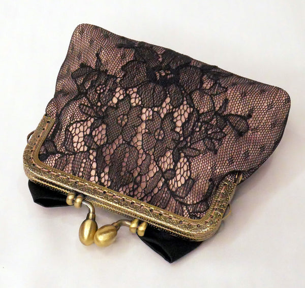 Small purse made of blush satin with a black lace overlay, black satin bow and antique brass frame.