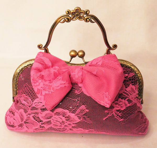black sequin handbag with a pink lace overlay and pink bow, attached to an antique brass frame with a handle