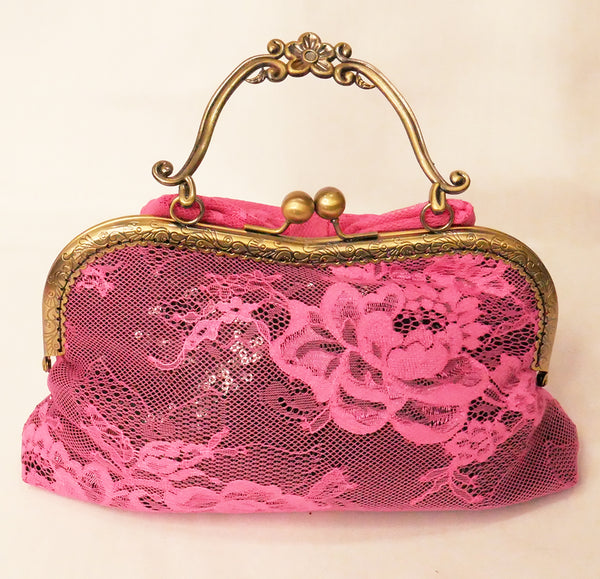 black sequin handbag with a pink lace overlay and pink bow, attached to an antique brass frame with a handle