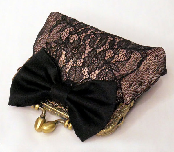 Small purse made of blush satin with a black lace overlay, black satin bow and antique brass frame.