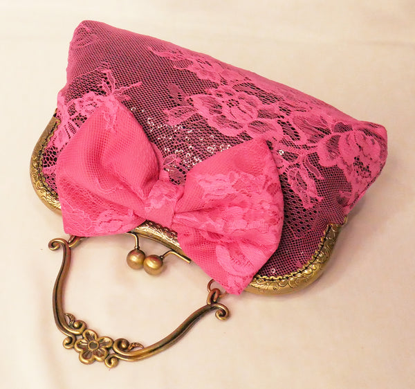 black sequin handbag with a pink lace overlay and pink bow, attached to an antique brass frame with a handle
