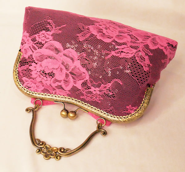 black sequin handbag with a pink lace overlay and pink bow, attached to an antique brass frame with a handle